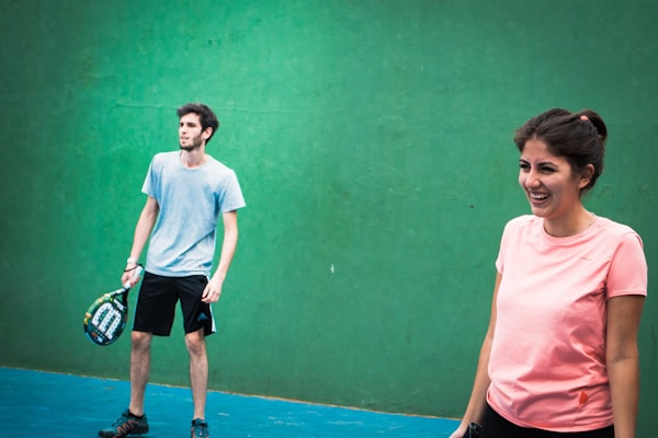 a woman holding a tennis racquet standing next to a man